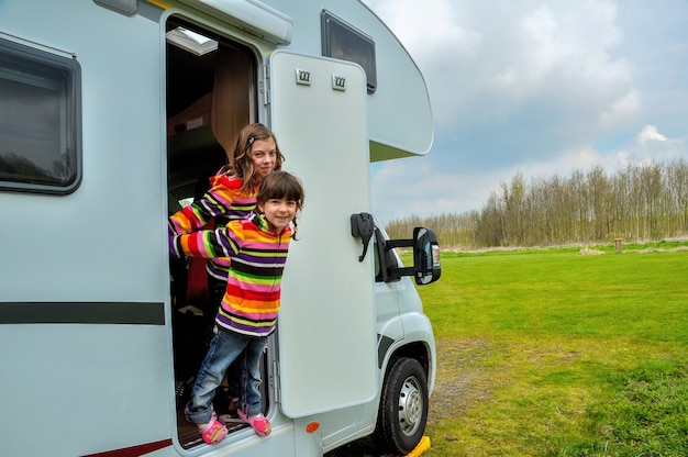 Happy kids near camper RV having fun, family vacation trip in motorhome