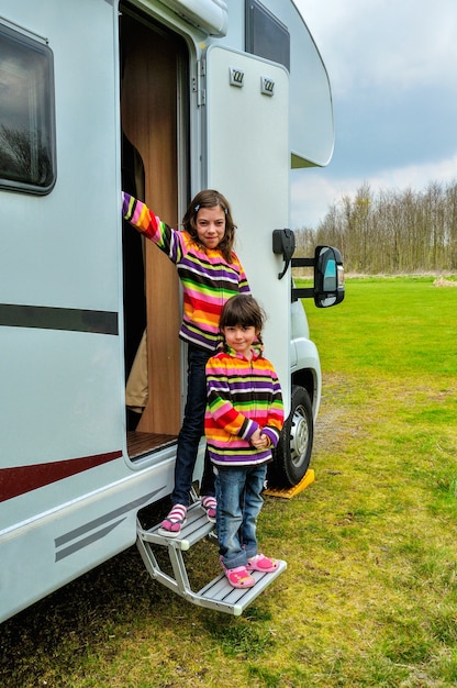happy kids near camper rv having fun, family vacation trip in motorhome