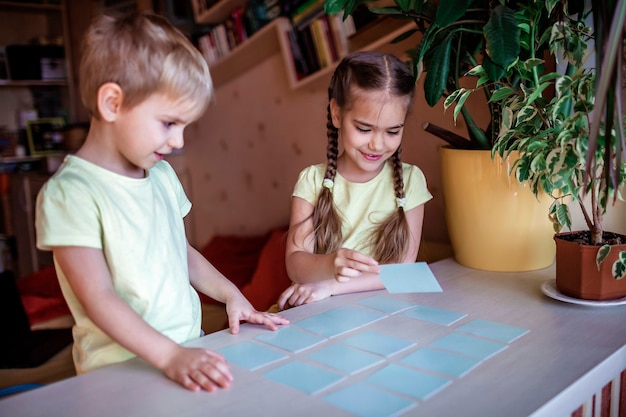 Bambini felici che giocano al memo del gioco da tavolo negli interni domestici, i valori della famiglia in realtà, stanno a casa, la vita durante la quarantena