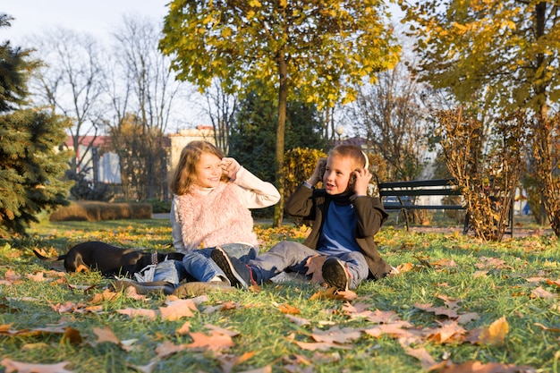 Happy kids playing with dog in sunny autumn park