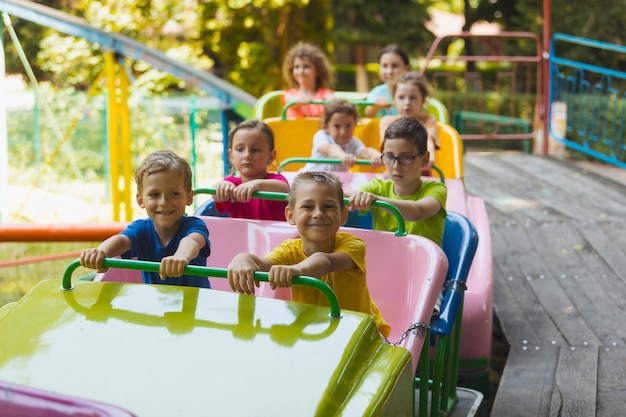 The happy kids on a roller coaster in the amusement park