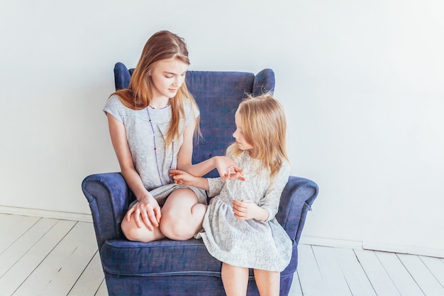 happy kids sitting on cozy blue chair relaxing playing at home