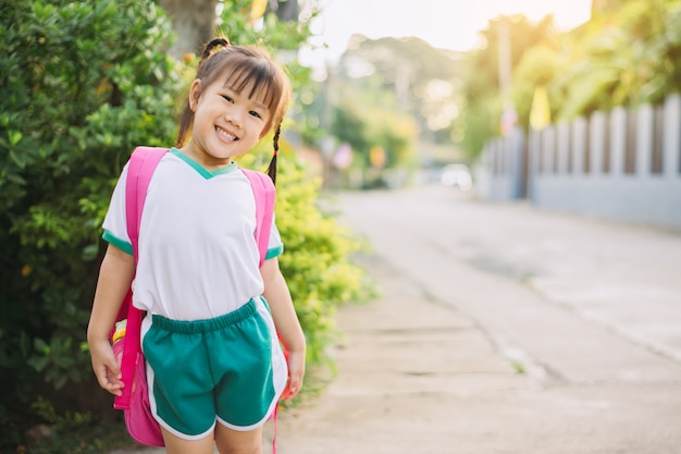 学生のスーツとバッグを学ぶために学校に行く準備ができて幸せな子供たち