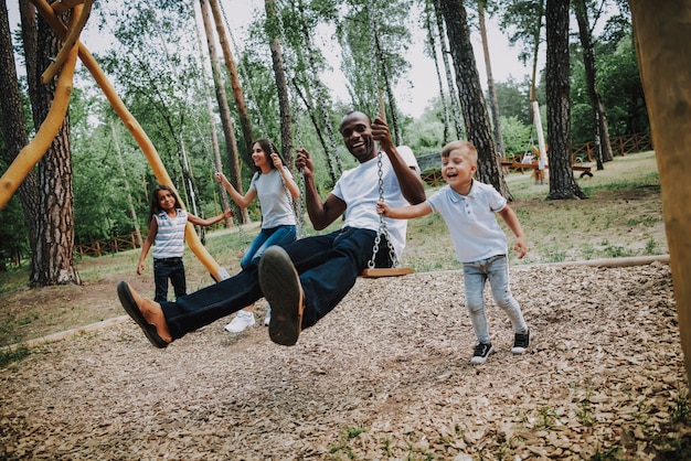 Photo happy kids swinging parents in park on swings