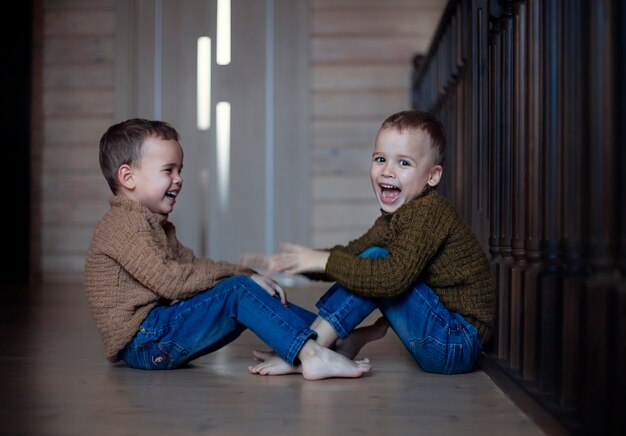 写真 幸せな子供たちの双子の兄弟が家で遊んでいます