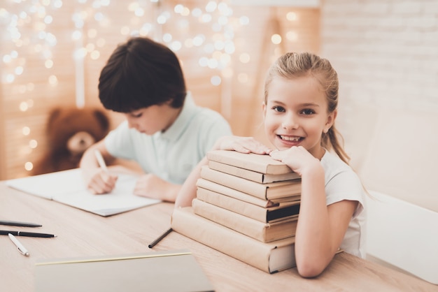 Foto bambini felici con libri di testo impilati alla scrivania