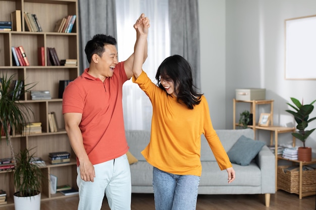 Happy korean spouses having fun at home dancing