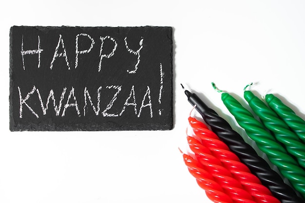 Happy Kwanzaa concept AfroAmerican vakantie Felicitatie belettering en zeven kaarsen rood zwart en groen Afrikaans erfgoed symbool op witte achtergrond