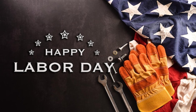 Happy Labor day concept American flag with different construction tools on dark stone background