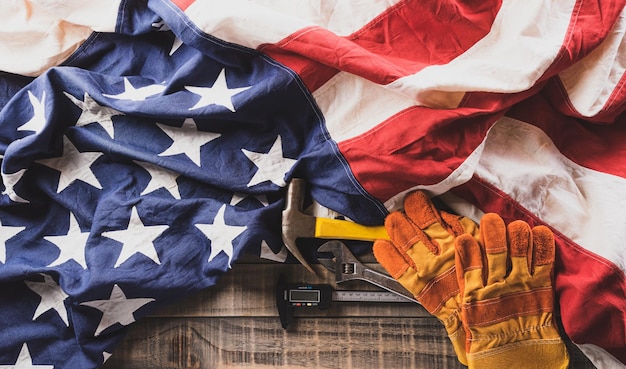 Happy Labor day concept American flag with different construction tools on dark wooden background