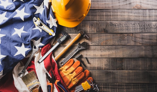 Foto happy labor day concept bandiera americana con diversi strumenti di costruzione su uno sfondo di legno scuro