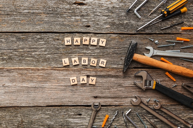 Happy labor day on wooden blocks and construccion tools on wooden background top view