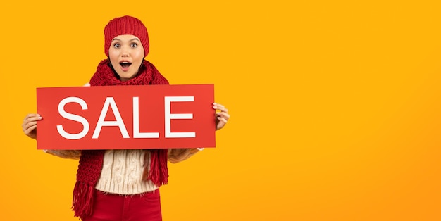 Photo happy lady in hat and scarf holding sale sign studio