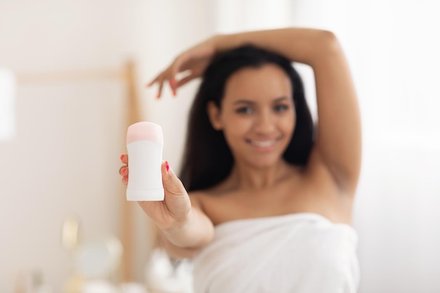 Happy lady showing antiperspirant to camera in modern bathroom