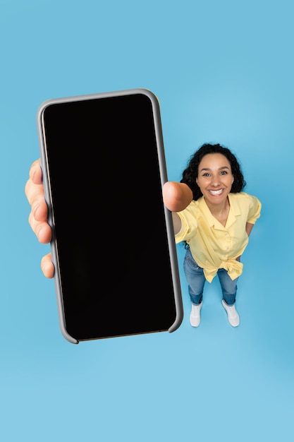 Happy lady showing blank mobile phone screen at studio