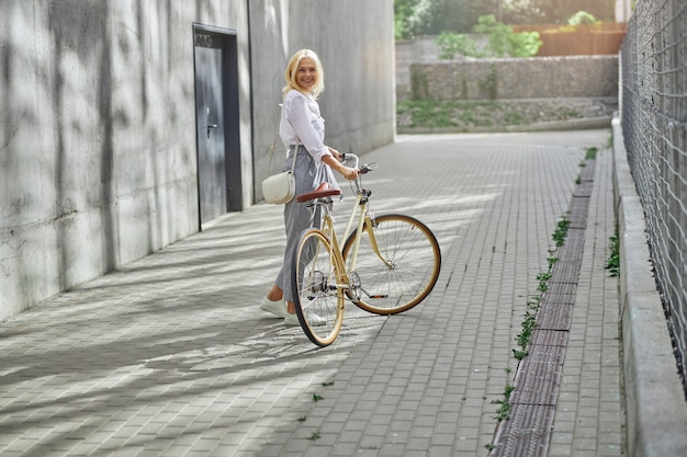 Happy lady using ecological transport by bicycle in the big city while going to the job