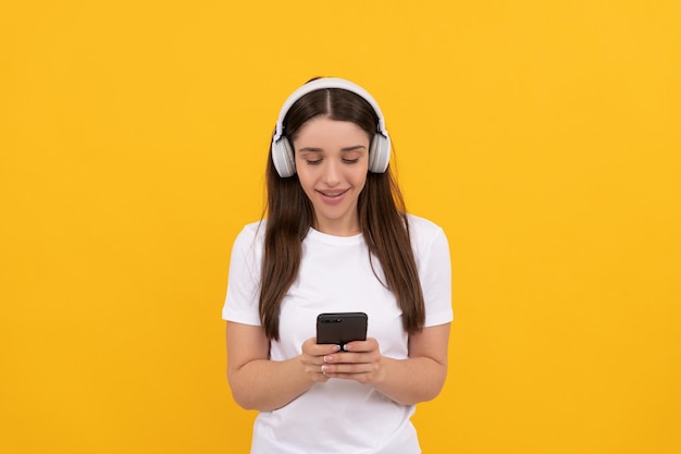 Happy lady in white shirt listening music in headphones and chatting on phone, music