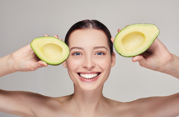 Happy lady with perfect smiling with avocado in hands