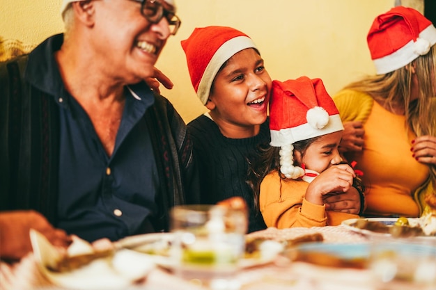 クリスマスの時期に一緒に食事を楽しんでいる幸せなラテン家族は兄弟の顔に焦点を当てる