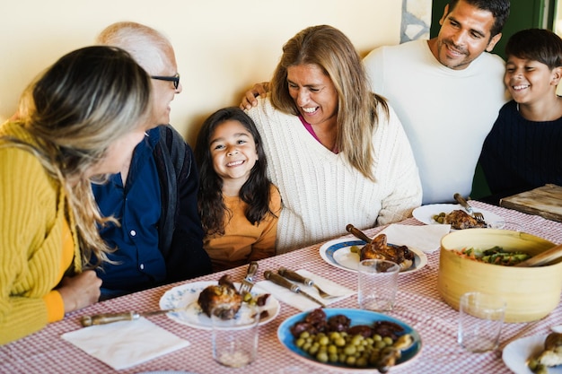 Happy latin family having fun eating together at patio restaurant - Focus on girl face