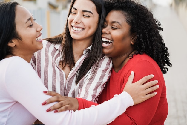 Happy latin girls having fun together outdoor around city - Main focus on african woman face