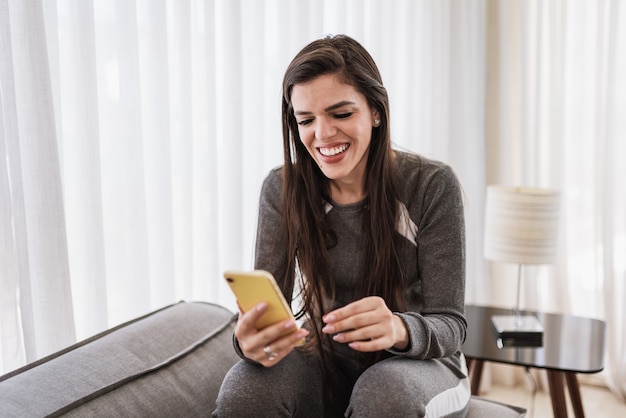 Happy Latin lady relax at home alone sit on room pose share good news at social media