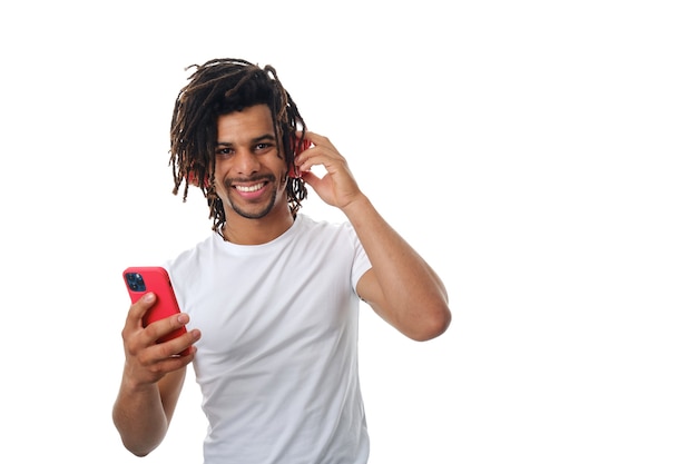 Foto felice uomo latino che si diverte ad ascoltare musica con un telefono cellulare e cuffie wireless.