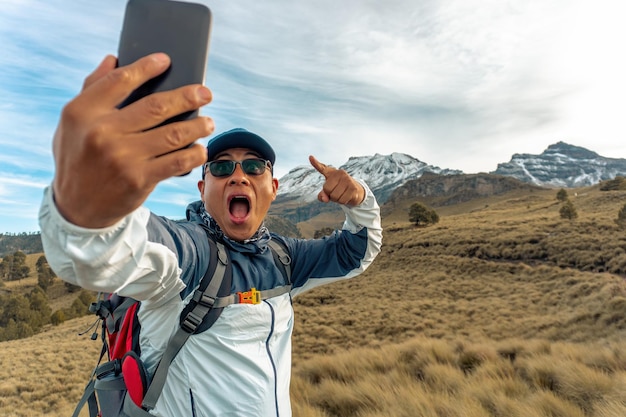 Foto felice uomo latino escursionista prendendo un selfie sul bordo della montagna