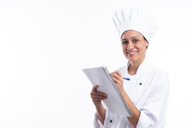 Happy latina cook writing down recipes in her notebook looking at camera isolated on white background with copy space