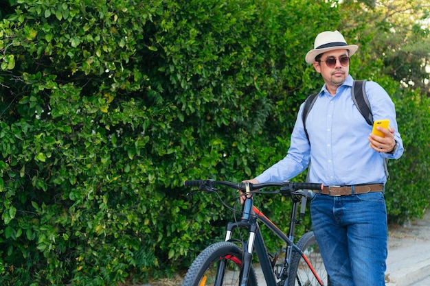 자전거를 걷는 동안 휴대폰을 확인하는 행복한 라틴계 남자