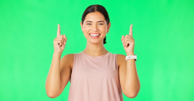 Happy laugh woman face and pointing up to show promotion and product placement in green screen Happiness smile and model gesture to advertising and commercial deal in isolated studio background