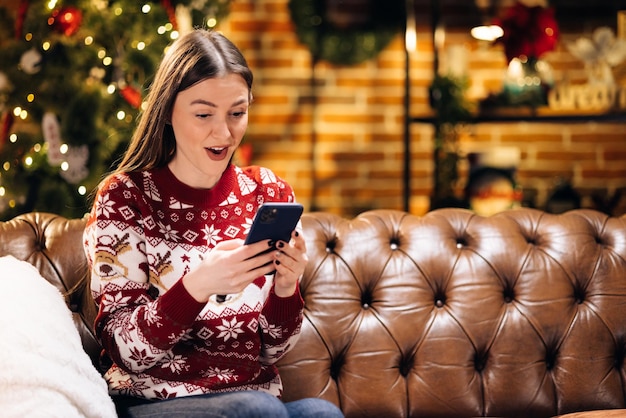 Happy laughing amazed caucasian woman looking at smartphone screen getting message with unbelievable