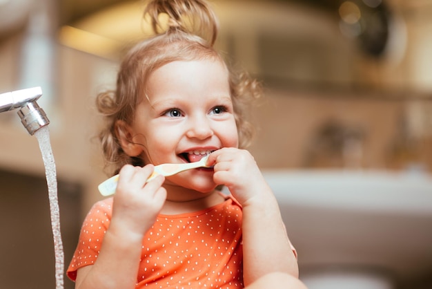 Happy laughing baby girl brushing her teeth in the bath