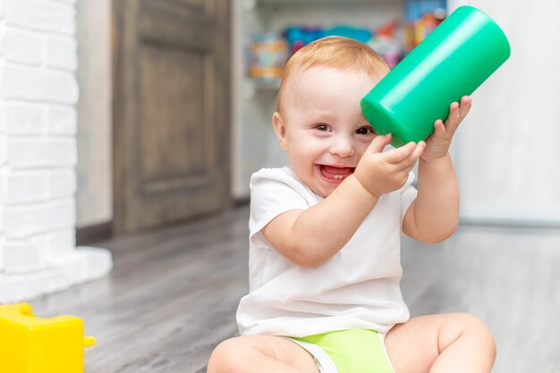 Happy laughing child playing with toy while sitting on the floor at home