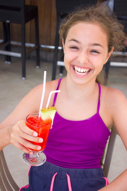 Ragazza ridendo felice con cocktail rosso in mano