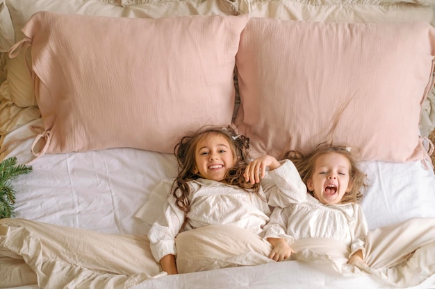 Photo happy laughing kids in pajamas early christmas morning having fun in bed