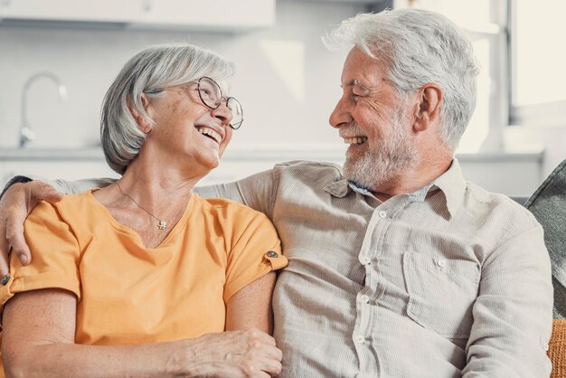 Фото Счастливая смешная пожилая супружеская пара разговаривает, смеется, стоит в интерьере дома вместе, обнимается с любовью, наслаждается близкими отношениями, доверяет, поддерживает, заботится, чувствует радость, нежность.