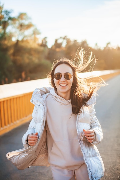 Happy laughing woman in warm clothes running outdoors during autumn season Freedom concept