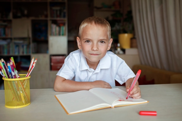 Happy lefthanded boy writing in the paper book with his left hand international lefthander day