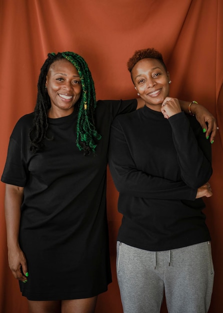 Happy lesbian couple standing by a red background