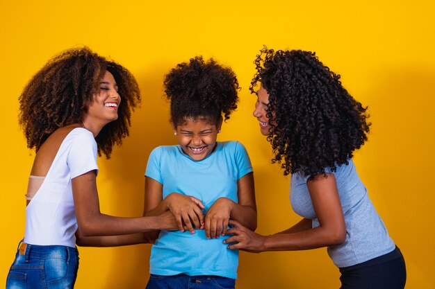 Happy lesbian couple with child on yellow background. Couple together with adoptive daughter, adoption concept