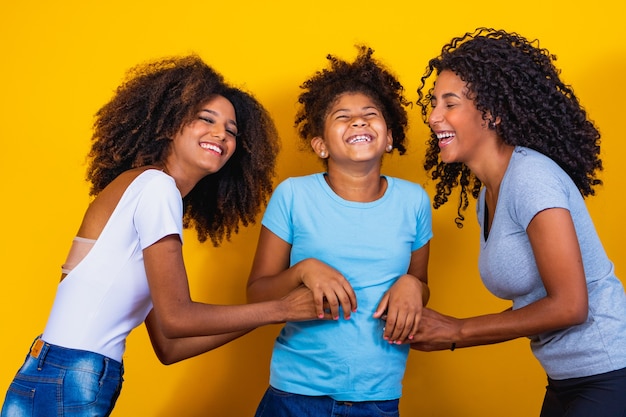 Photo happy lesbian couple with child on yellow background. couple together with adoptive daughter, adoption concept