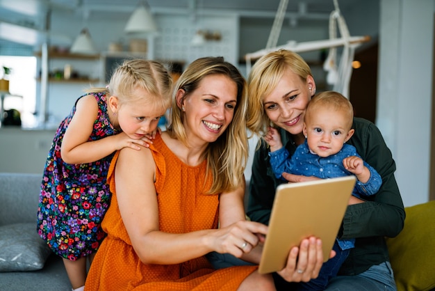 Happy lesbian couple with little adopted girl at home. Homosexual, lgbt, people concept.