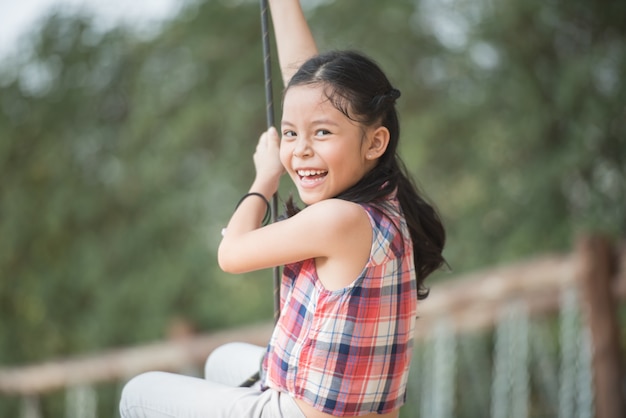 Foto piccolo bambino asiatico felice della ragazza che si diverte a giocare nel campo da giuoco nell'ora legale con il sorriso e il bambino femminile adorabile adorabile del fronte sorridente sano e divertente di risata.