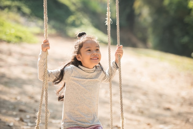 写真 夏の遊び場で笑顔で遊んで、健康的に笑って楽しんでいる幸せな小さなアジアの女の子の子供、夏のブランコで楽しんでいる愛らしい女の子。