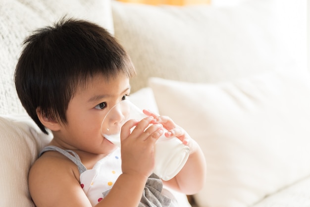 幸せなアジアの女の子の手を飲む牛乳のガラス