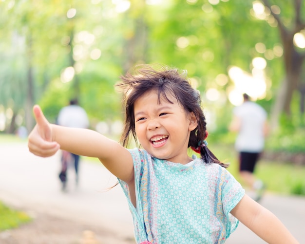 幸せなアジアの女の子を再生し、面白い瞬間で大きな木を求める。