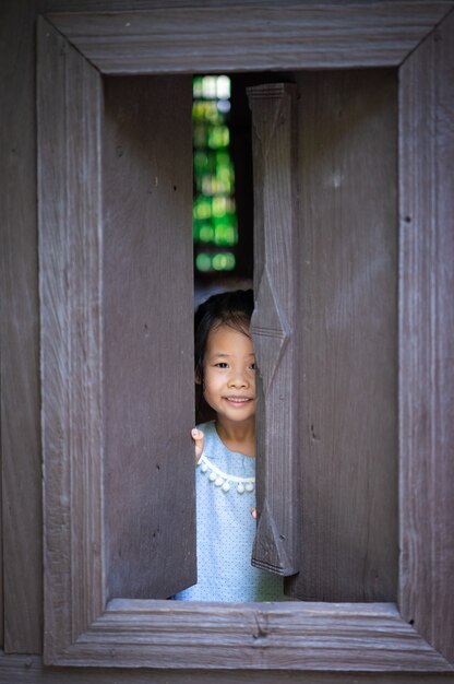 幸せな小さなアジアの女の子が立っているとウィンドウを開く