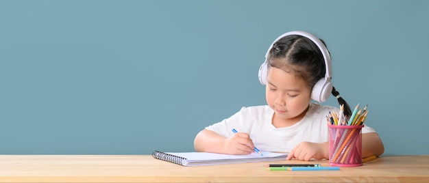 Счастливая маленькая азиатская девочка изучает онлайн-класс обучения с учителем масштабирования онлайн-видеозвонка дома. Электронное обучение или концепция домашнего образования. Новый нормальный. Коронавирус COVID-19. Социальное дистанцирование.