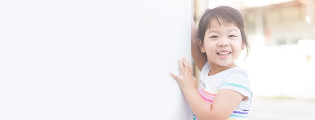 Happy little asian girl behind a white banner board.